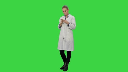 Female Doctor Text a Message Using Modern Smartphone on a Green Screen, Chroma Key.