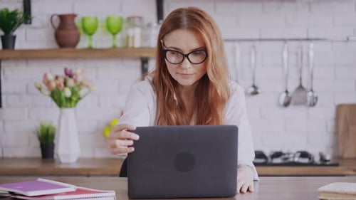 Woman Opens Laptop and Smiles in Kitchen