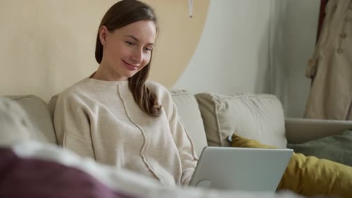 Woman Using Laptop Relaxing on Couch at Home