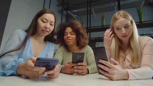 Good Looking Multiracial Women Networking on Cellphones at Cafe