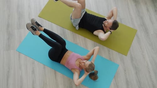 High Angle View of Beautiful Young Couple Training Abdominal Muscles Exercising Together at Home