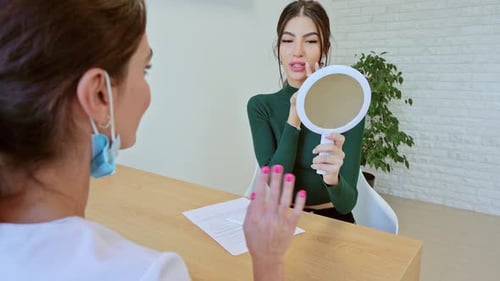 Young Woman Checking Lips in Mirror at Clinic