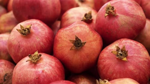 Many Red Pomegranate Closeup Rotating on Background in Store for Buyer.