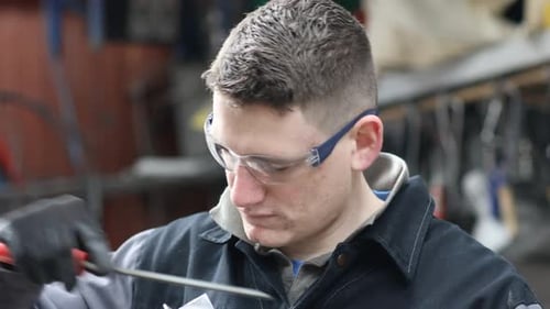Handwerker feilt Metall in Werkstatt
