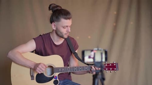 Man Plays Acoustic Guitar While Recording Performance