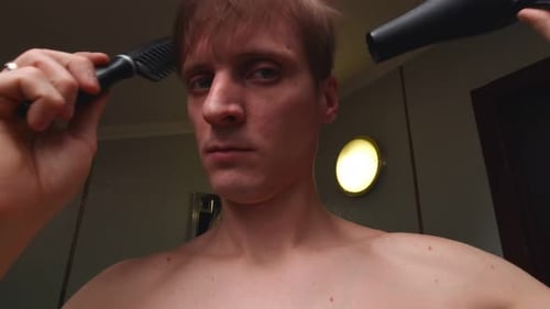 Young Man Combs and Blow Dries Hair