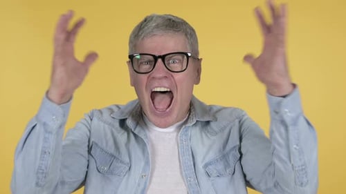 Mature Man Yelling in Frustration Against Yellow Background