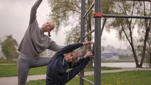 Mother and Daughter Doing Exercises on Open Air Sport Playground