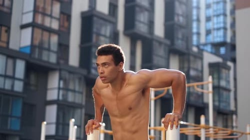 Muscular Man Exercising Outdoors on Dip Bars