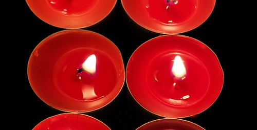 Glowing Red Tea Candles Reflecting on Black Surface