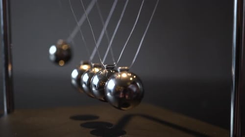 Closeup Video of Metal Newton Cradle Swining on Gray Background