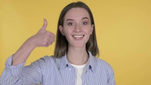 Young Woman Giving Thumbs Up on Yellow Background