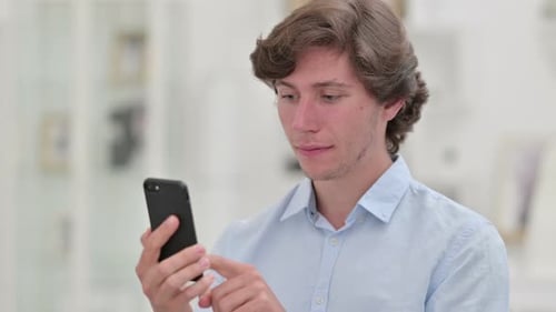 Young Man Uses Smartphone Indoors During Daytime