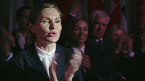 Woman Giving Speech at Podium with Flags Behind