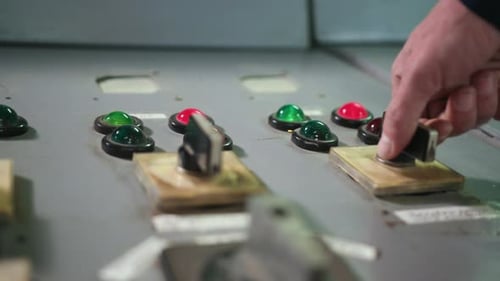 Hand Turns Lever on Industrial Control Panel