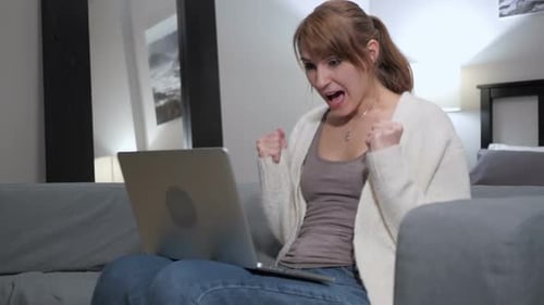 Woman Working on Laptop Receives Good News and Celebrates
