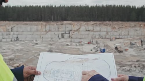 Workers Discussing Blueprint at Mining Site