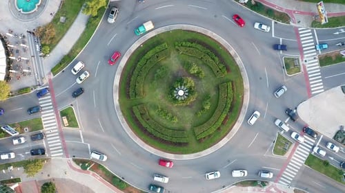 Vehicles on a busy roundabout junction. Traffic circle with a lot of cars. Top down aerial view
