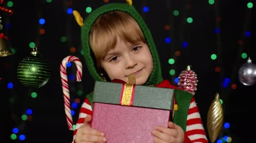 Cheerful Child Dressed as Elf Presents Christmas Gift
