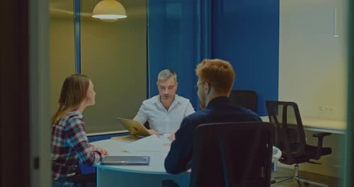 Young Businessmen are Sitting at a Meeting in a Modern Coworking Office and Talking About the