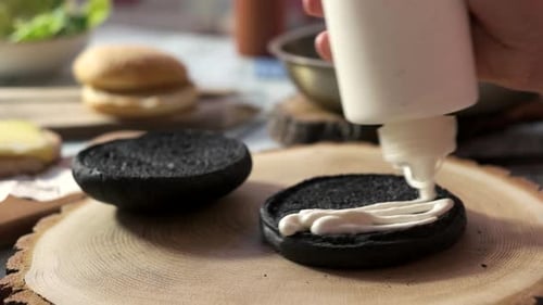 Sauce Being Applied to Black Bun Burger