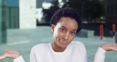 Im Freien Porträt einer verwirrten verärgerten, ahnungslosen emotionalen afrikanischen Frau Mädchen zuckt mit den Schultern und schaute
