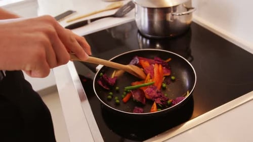 Man Frying Vegetables in Pan on Stove