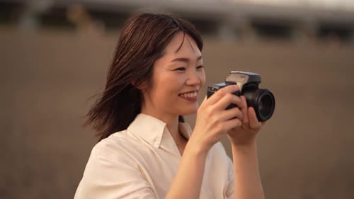Woman Photographer Taking Pictures on Beach at Sunset