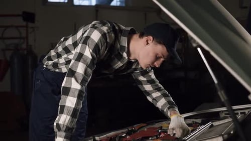 Young Mechanic Working on Car Engine in Garage