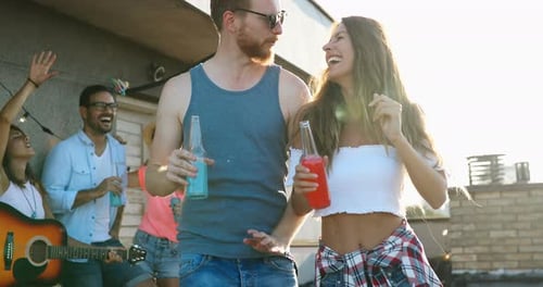 Friends Celebrate at Rooftop Party with Drinks and Music