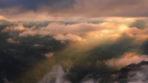 Nuages bas sur un plateau montagneux sous les rayons du soleil couchant
