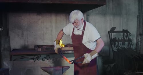 Senior Blacksmith Forging Red Hot Metal on Anvil