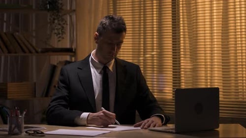 Man Working at Desk in Dark Office at Night
