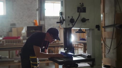 Carpentry Workshop Worker Cutting a Wooden Board with an Automatic Saw