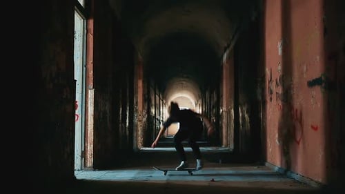 Skateboarder Does Tricks in a Dark Hallway