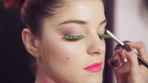 Vista de cerca de un artista de maquillaje hace que las modelos maquille los ojos con pestañas postizas