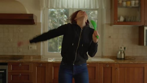 Woman Dancing with Spatula in Bright Kitchen