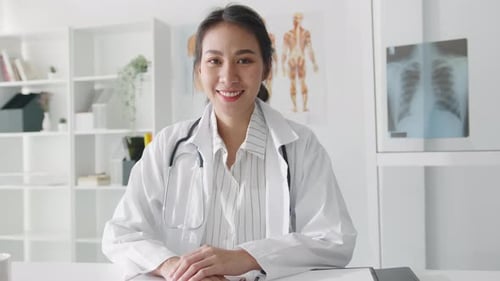 Confident young Asian female doctor looking at camera and smiling in health hospital