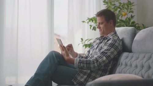 Man Relaxing on Couch Using Tablet Device