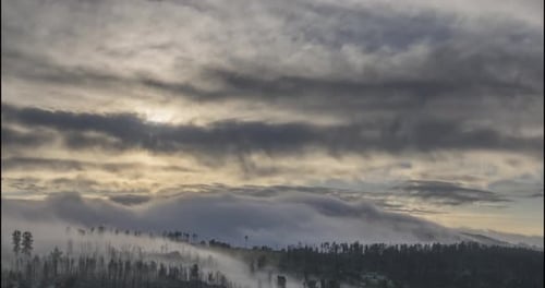 Timelapse de los rayos del sol de la tarde emergiendo a través de las frías nubes brumosas en las montañas