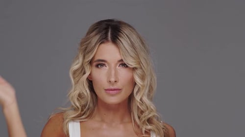 Studio portrait of young and beautiful blond woman over grey background.