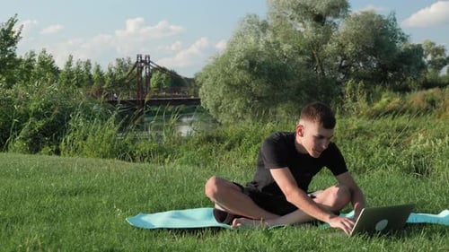 Yoga in morning city park. Man practicing yoga on fitness mat on grass.
