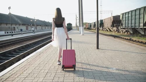 Woman Walks at a Train Station with Suitcase
