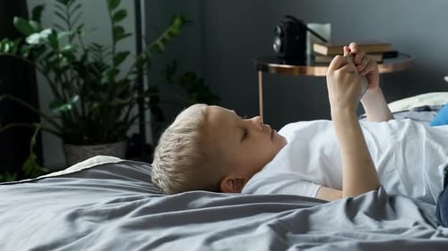 Close-up View from the Side A Child Boy Looks at the Phone Screen Plays a Game on A Smartphone