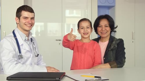 Doctor, Child and Adult Smiling in Medical Office