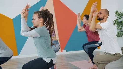 Girls and Guy Practising Eagle Position During Yoga Class in Modern Sports Center