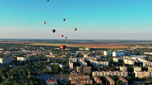 Multicolored balloons fly over trees. Nice top view of the park, forest covered with greenery.