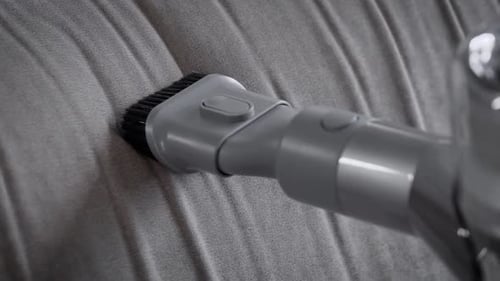 Close-up Cleaning the Sofa with a Hand-held Vacuum Cleaner.