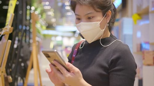Woman With Face Mask Using Smartphone Indoors