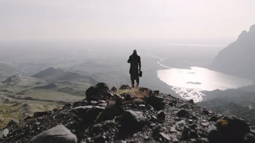 Drone Over Lone Traveller Looking Down Into Sunlit Valley